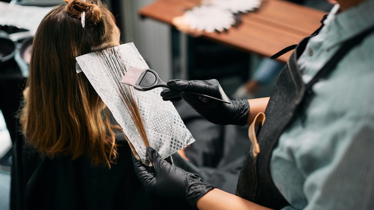 Friseure färbt einer Kundin eine Haarsträhne